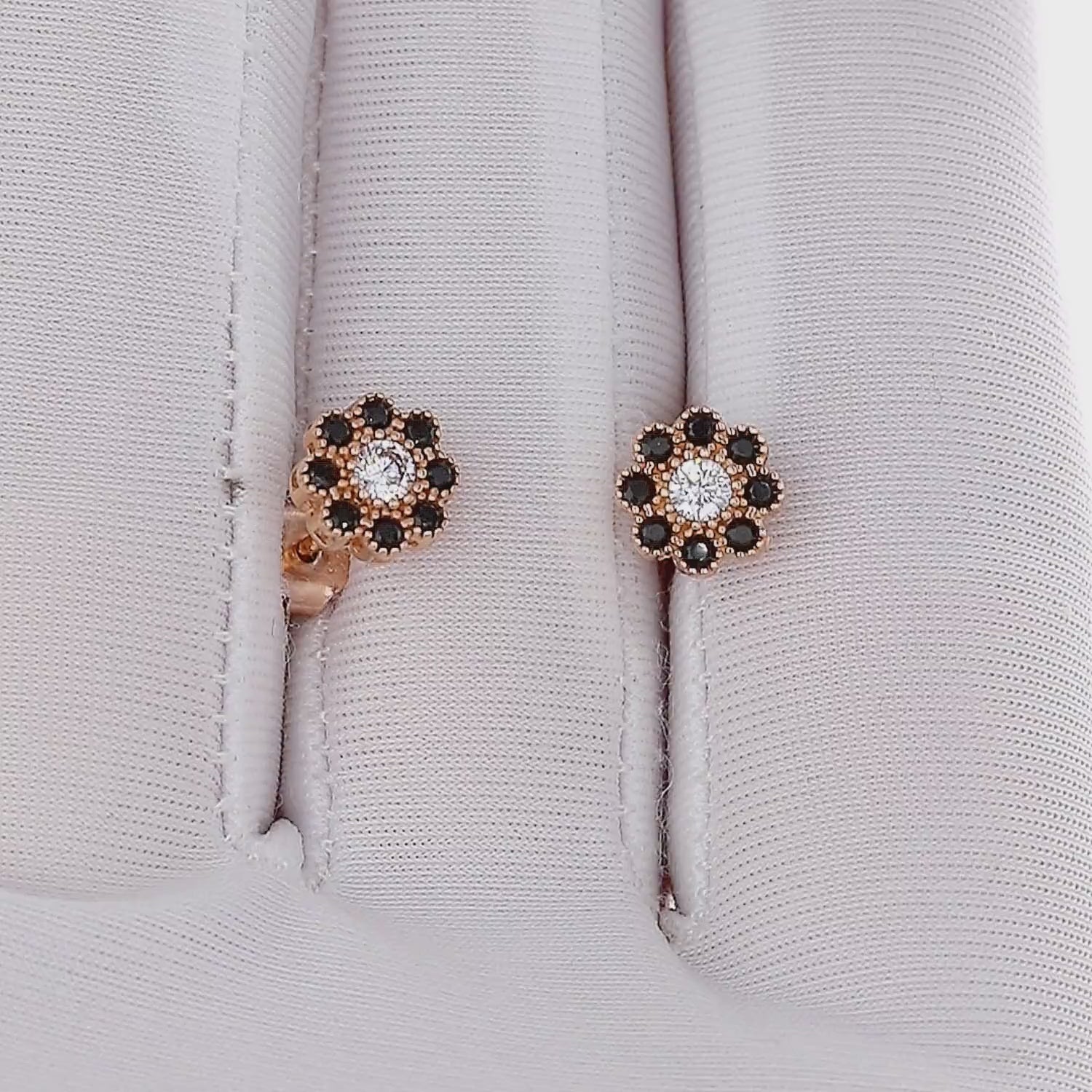 Auksiniai gėlytės formos auskarai su baltais ir juodais cirkoniais – realus žvilgesys ir dizaino detalės judesyje.